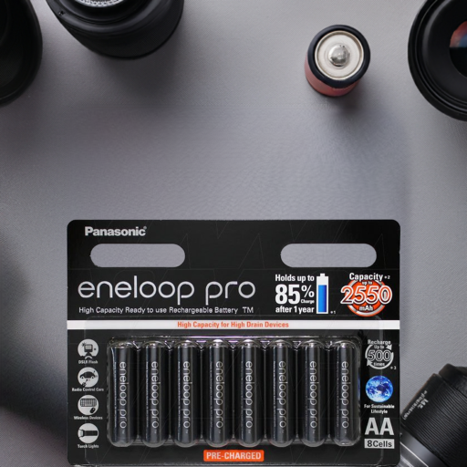 Packaging of Panasonic eneloop pro rechargeable batteries on a gray surface with camera equipment in the background.